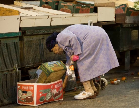 תמונה של אישה מבוגרת שמחפשת אוכל בפחים